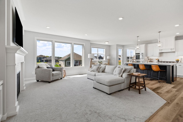 living area featuring light wood-type flooring, recessed lighting, a fireplace, and baseboards