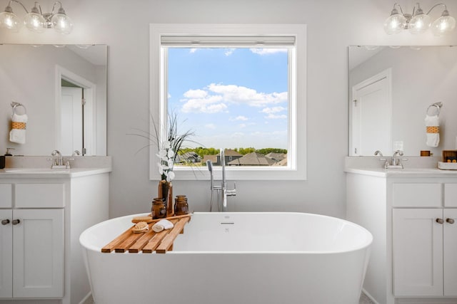 bathroom with a wealth of natural light, a soaking tub, two vanities, and a sink