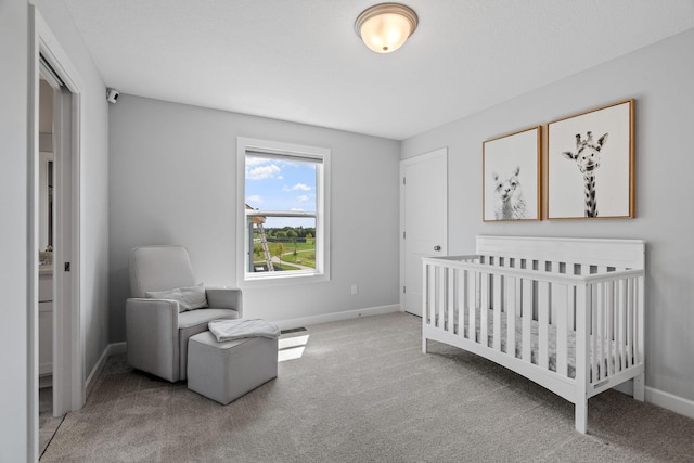 bedroom with carpet floors, a crib, and baseboards