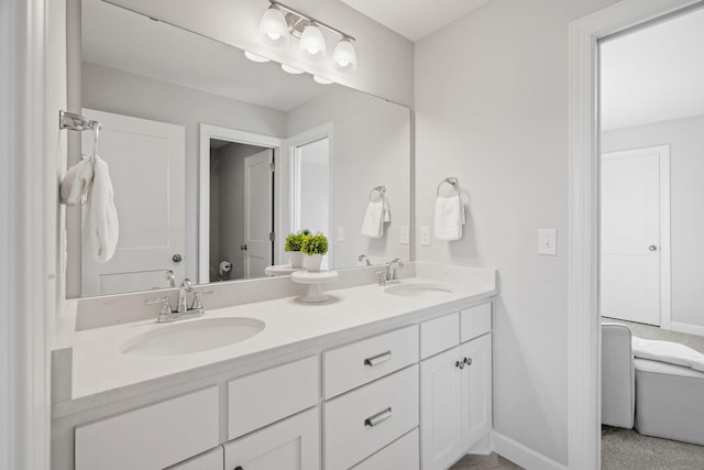 full bath with double vanity, a sink, and baseboards