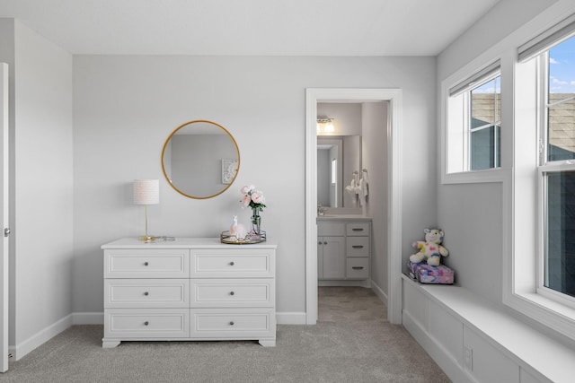 interior space with baseboards, ensuite bathroom, and light colored carpet