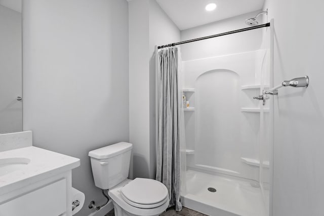 bathroom featuring vanity, a shower stall, and toilet