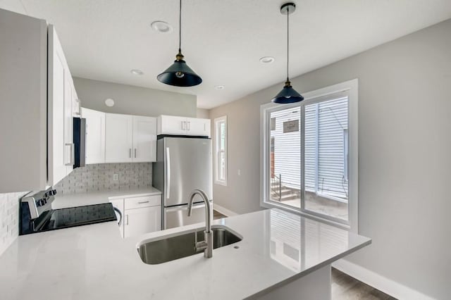 kitchen featuring white cabinets, decorative light fixtures, appliances with stainless steel finishes, and sink