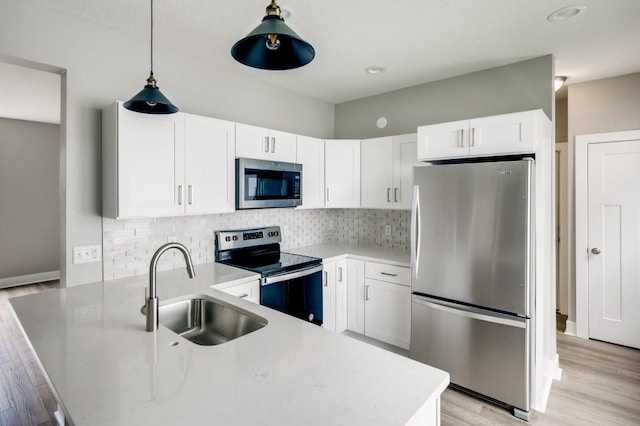 kitchen featuring sink, stainless steel appliances, hanging light fixtures, and white cabinets