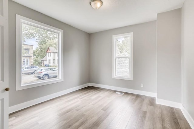 unfurnished room with a healthy amount of sunlight and light hardwood / wood-style floors