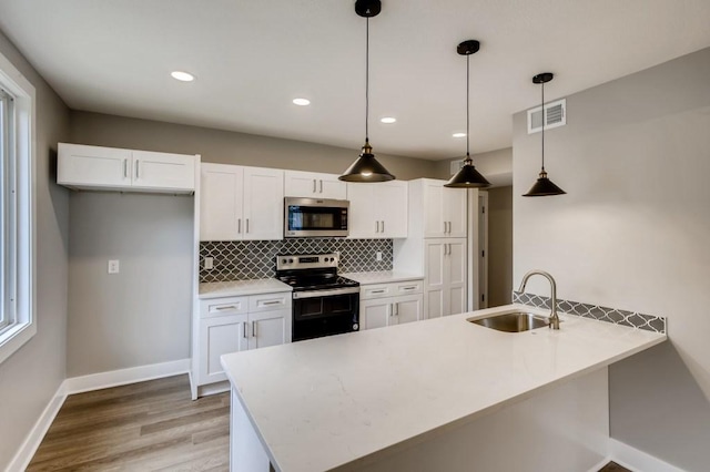 kitchen featuring decorative light fixtures, sink, white cabinetry, and stainless steel appliances