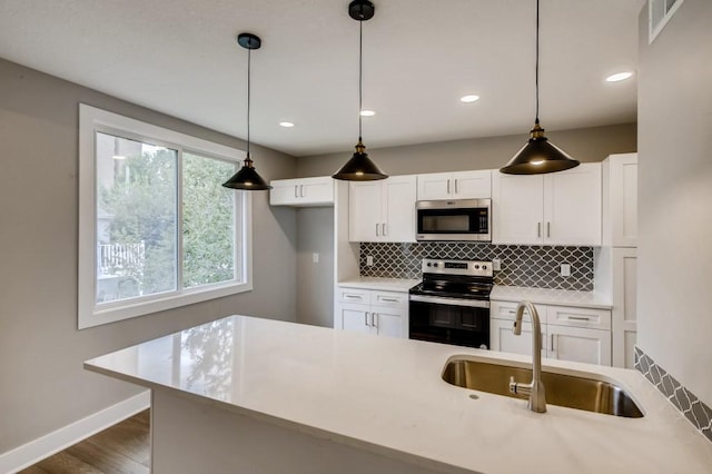 kitchen featuring sink, white cabinets, hanging light fixtures, and stainless steel appliances