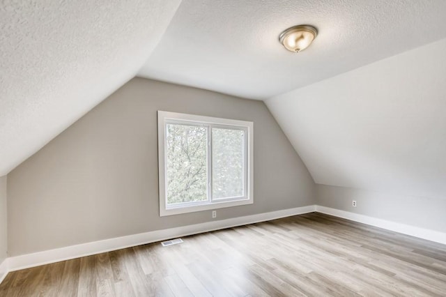 bonus room featuring a textured ceiling, light hardwood / wood-style flooring, and lofted ceiling