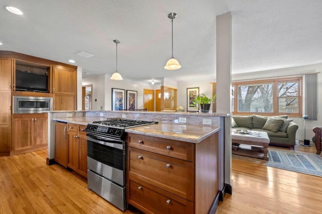 kitchen with brown cabinetry, open floor plan, light wood finished floors, and stainless steel appliances