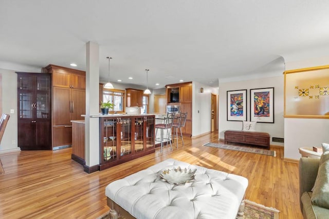 living area featuring recessed lighting, baseboards, and light wood-style floors