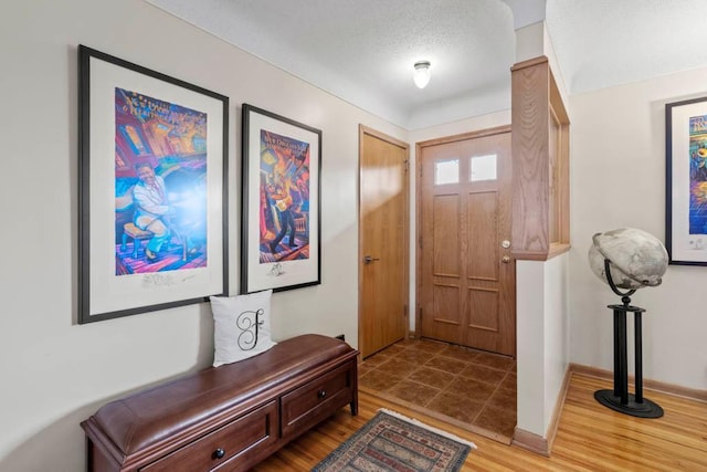 foyer entrance featuring wood finished floors, baseboards, and a textured ceiling