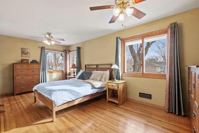 bedroom featuring light wood finished floors, a ceiling fan, and baseboards