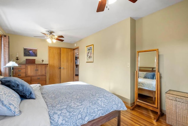 bedroom with radiator, baseboards, wood finished floors, a closet, and a ceiling fan