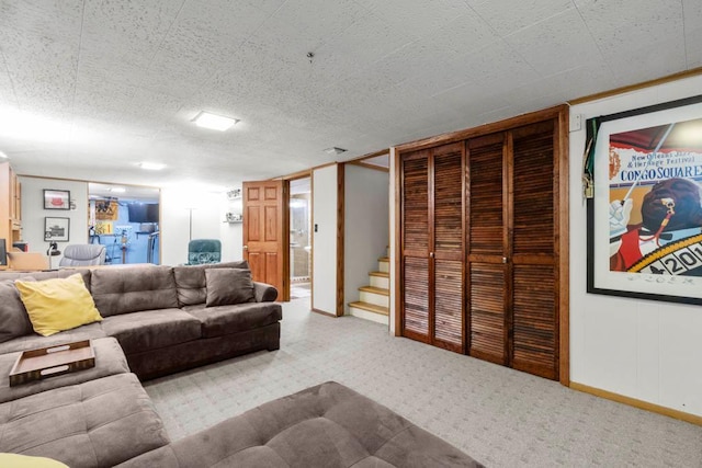 carpeted living area featuring baseboards and stairs