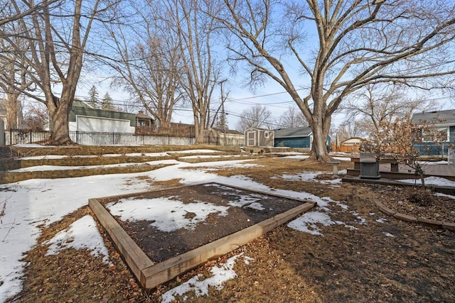 yard covered in snow featuring an outbuilding, a shed, and fence