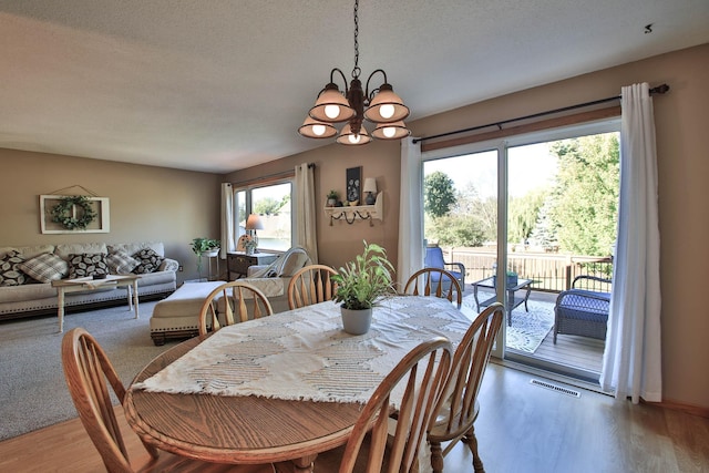 dining space featuring hardwood / wood-style flooring, an inviting chandelier, and a textured ceiling