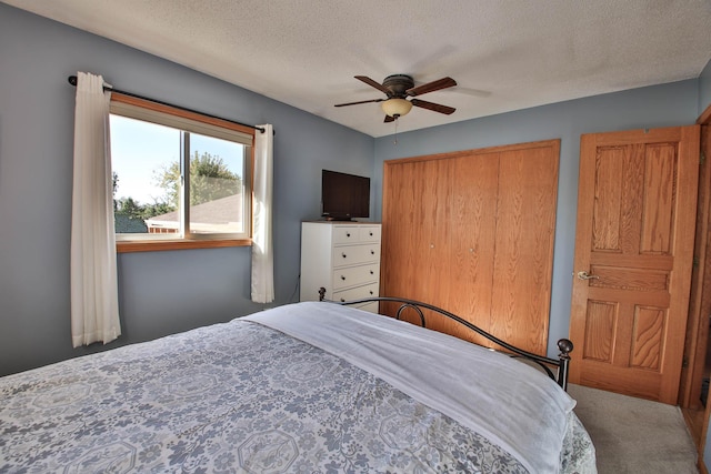 bedroom with ceiling fan, carpet, a textured ceiling, and a closet