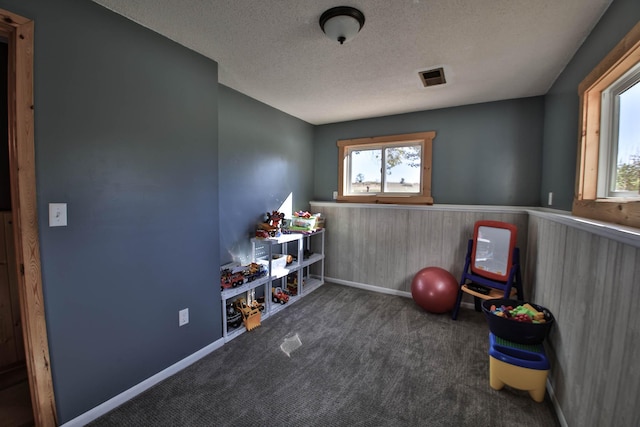 game room featuring a textured ceiling and dark carpet