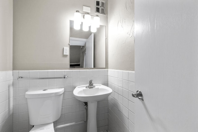 bathroom with toilet and tile walls