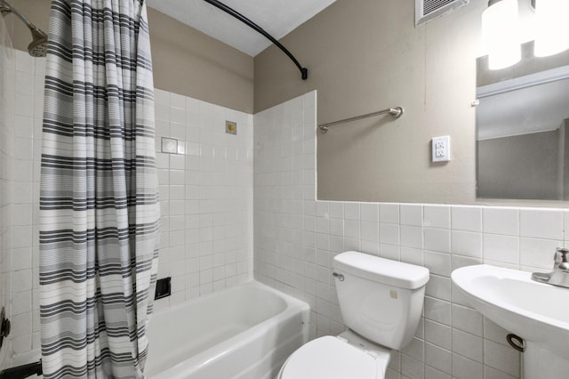 full bathroom with shower / bath combination with curtain, toilet, sink, and tile walls