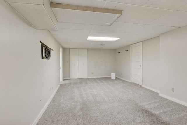 carpeted empty room featuring a drop ceiling