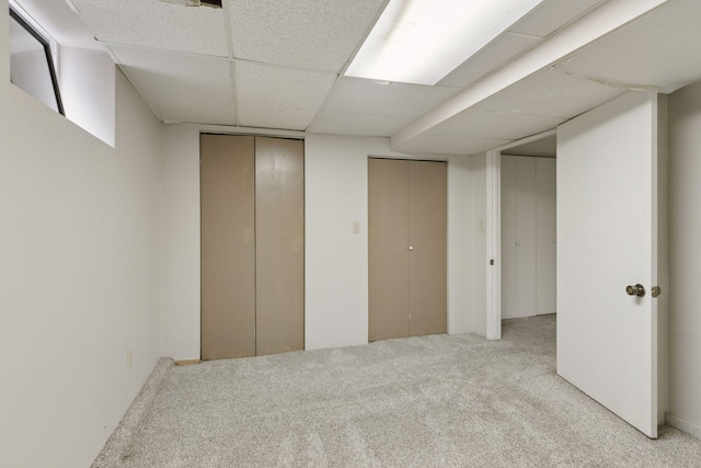 basement featuring elevator, light colored carpet, and a drop ceiling