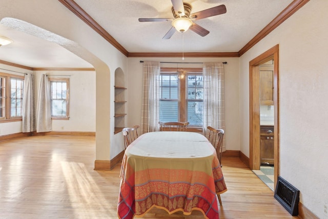 dining area with a wealth of natural light, built in features, a textured ceiling, and light wood-type flooring