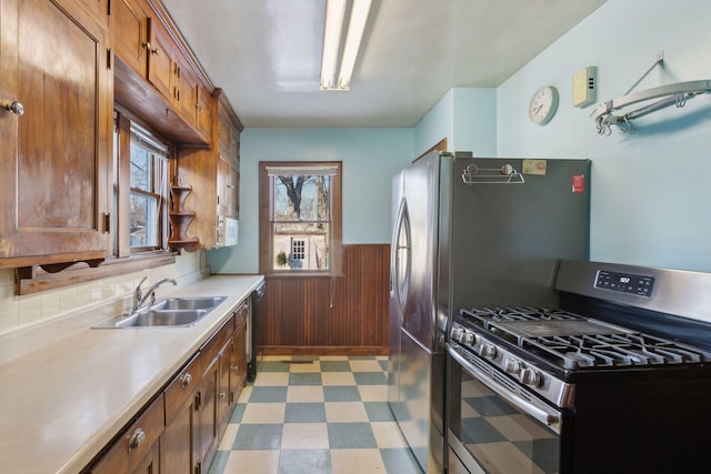 kitchen featuring sink, wood walls, and appliances with stainless steel finishes