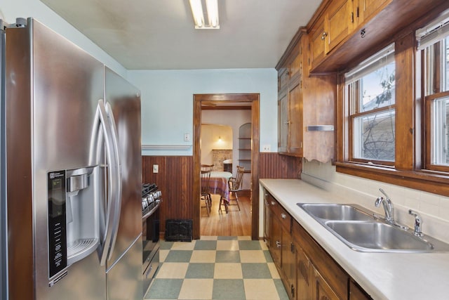 kitchen featuring sink, appliances with stainless steel finishes, and wood walls