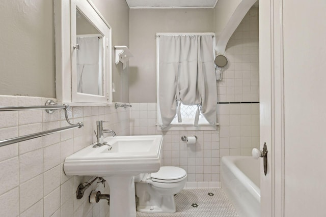 bathroom with tile walls, tile patterned floors, a bathing tub, and toilet