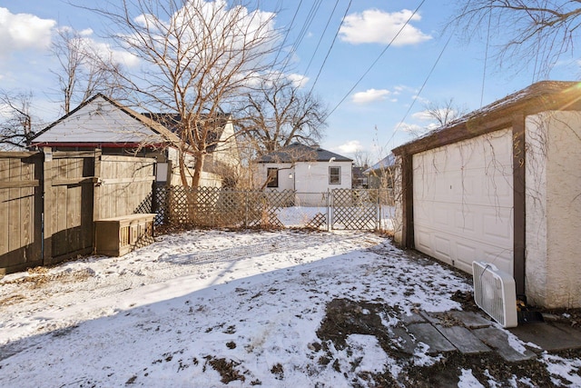 snowy yard featuring a garage and an outdoor structure