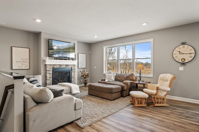 living room featuring wood-type flooring, a textured ceiling, and a fireplace