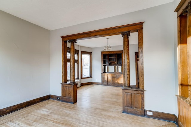 interior space with decorative columns and light hardwood / wood-style flooring