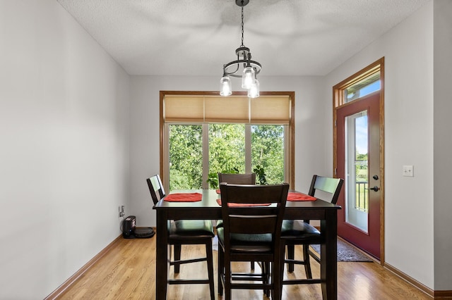 dining area featuring light wood-type flooring and a textured ceiling