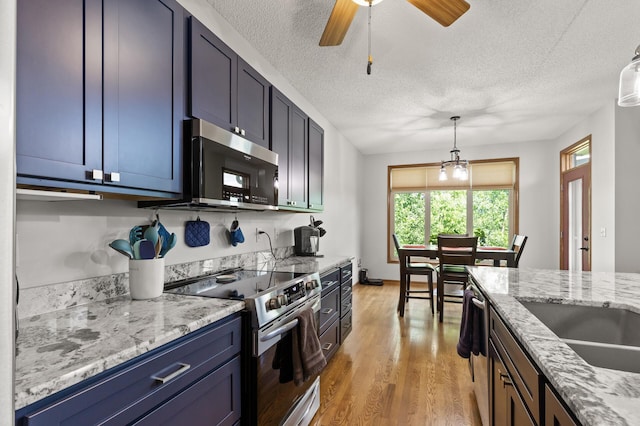 kitchen with light stone countertops, a textured ceiling, pendant lighting, stainless steel appliances, and blue cabinets