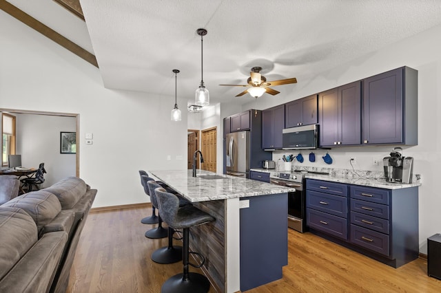 kitchen featuring pendant lighting, stainless steel appliances, an island with sink, sink, and a breakfast bar area