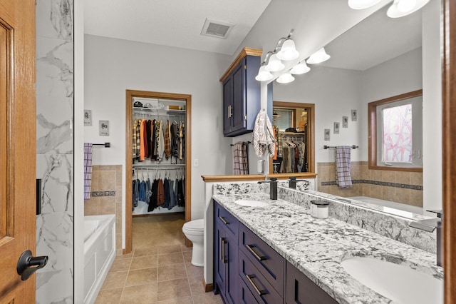 bathroom with vanity, toilet, tile walls, and tile patterned flooring