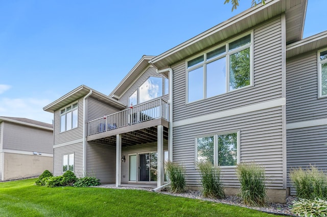 rear view of house with a balcony and a yard