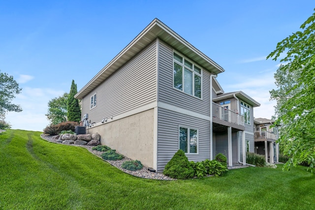 view of home's exterior with a balcony, central AC unit, and a lawn