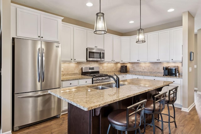 8160 Virginia Ln, Savage, MN 55378 - kitchen featuring appliances with stainless steel finishes, wood finished floors, tasteful backsplash, white cabinets, and a kitchen bar