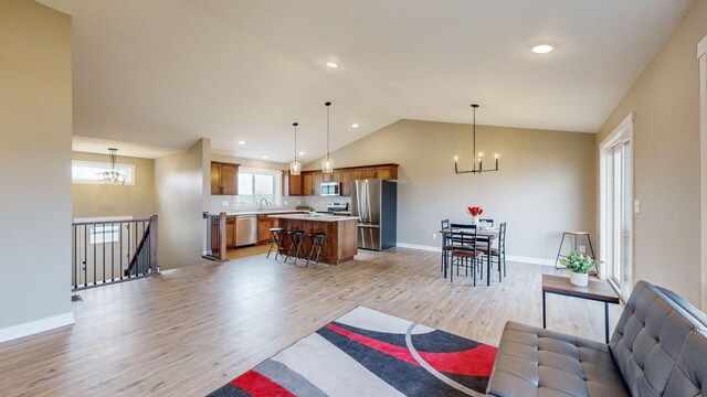 living room with light wood-type flooring, a chandelier, high vaulted ceiling, and sink