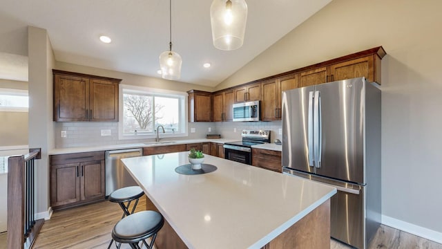 kitchen featuring sink, decorative light fixtures, a center island, decorative backsplash, and stainless steel appliances