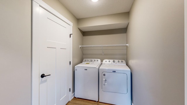 laundry room with light hardwood / wood-style flooring, a textured ceiling, and washer and dryer