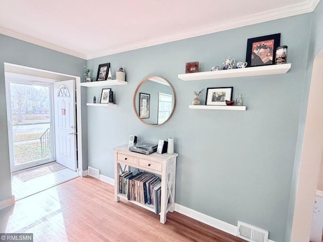 foyer with wood-type flooring and crown molding