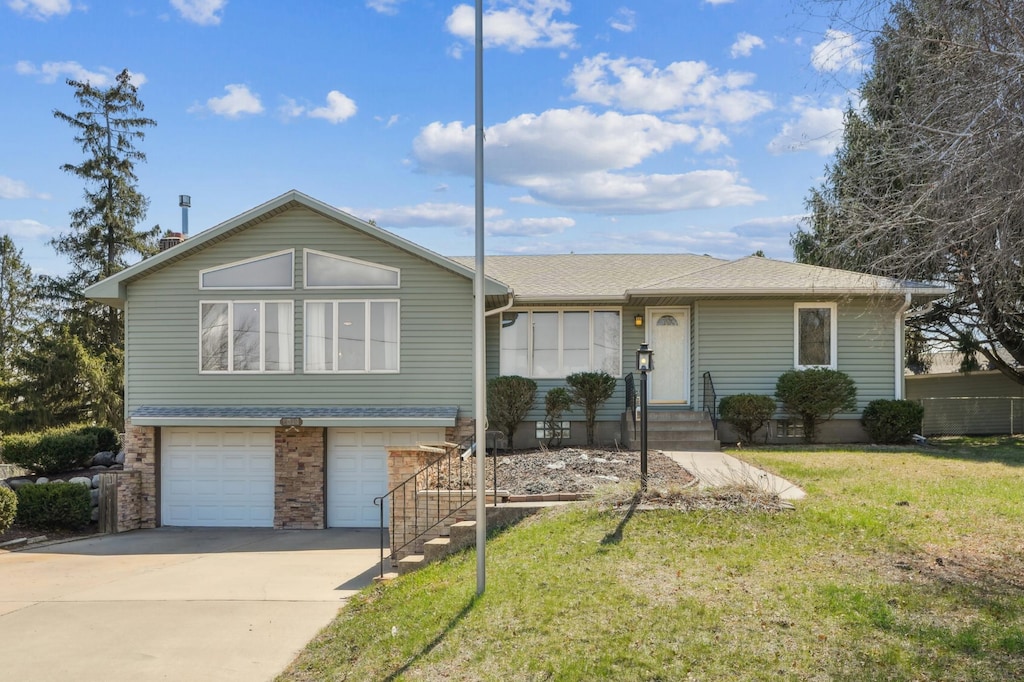 view of front of house with an attached garage, a shingled roof, a front yard, and concrete driveway