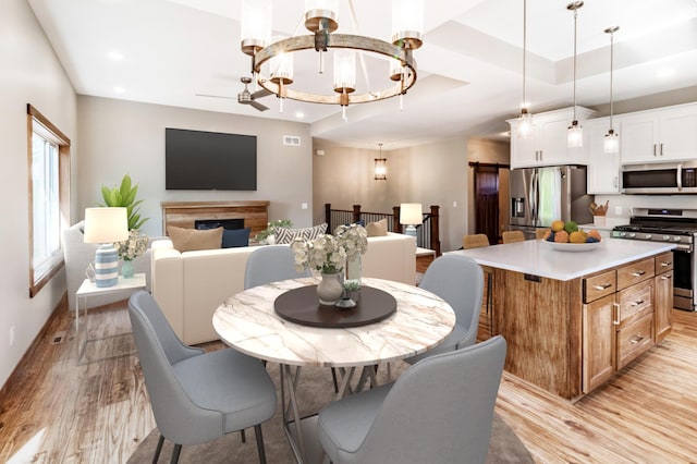 dining space featuring a raised ceiling and light hardwood / wood-style flooring