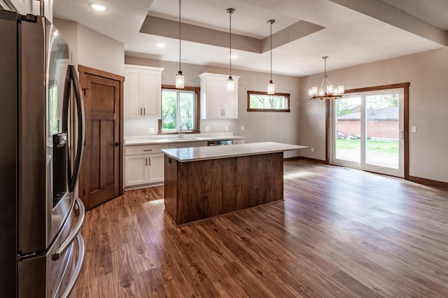 kitchen with white cabinets, a kitchen island, sink, a raised ceiling, and stainless steel fridge