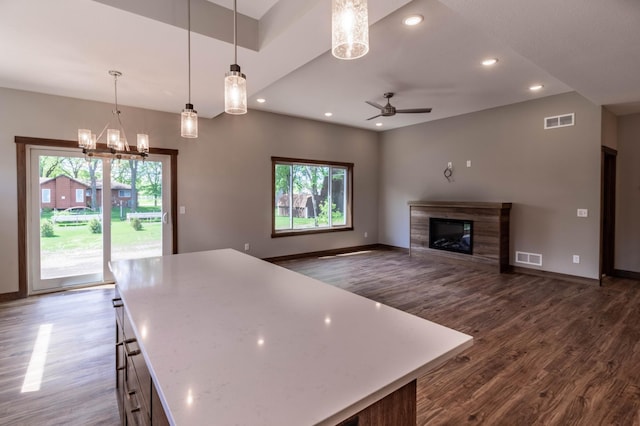 kitchen featuring ceiling fan with notable chandelier, a center island, hanging light fixtures, and dark hardwood / wood-style flooring