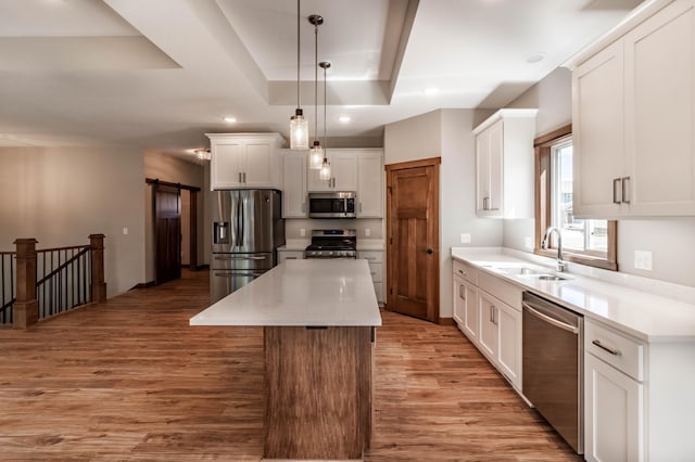 kitchen with white cabinets, a kitchen island, decorative light fixtures, stainless steel appliances, and sink