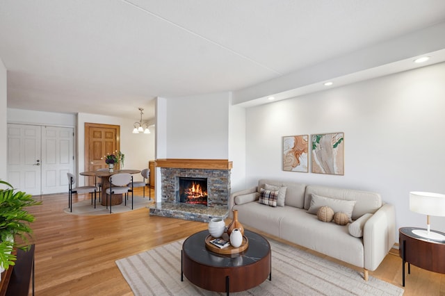 living room featuring a notable chandelier, a fireplace, and light wood-type flooring